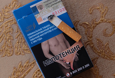 Окурок на пачке сигарет с акцизной маркой и картинкой о вреде курения
