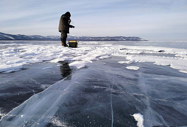 Подледная рыбалка в Бурятии. Рыбак-любитель ловит байкальского омуля со льда Байкала