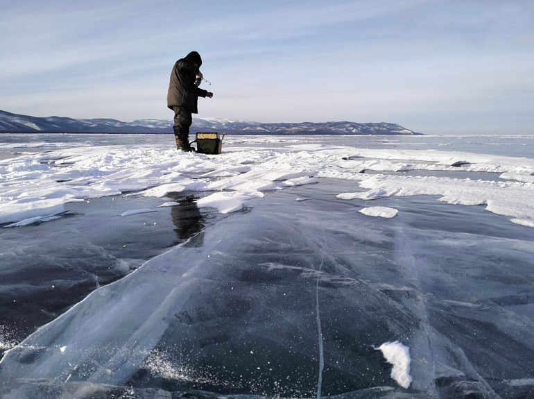 Подледная рыбалка в Бурятии. Рыбак-любитель ловит байкальского омуля со льда Байкала