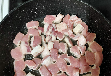 Кусочки нарезанной свинины на сковородке