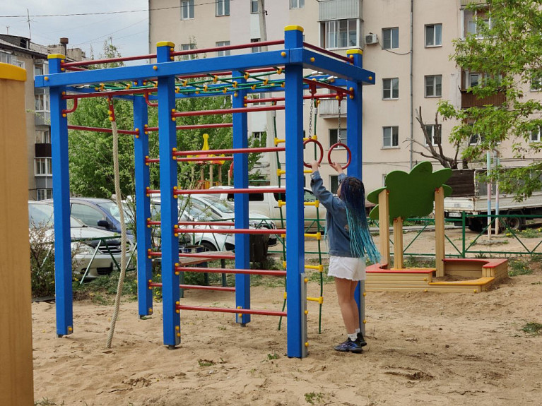 Ребенок на уличной детской площадке. Детский спортивный комплекс со шведской стенкой во дворе дома