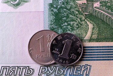 Российские и китайские деньги. Купюра в пять рублей и монеты в один рубль и один цзяо