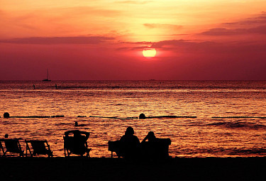 Туристы на пляже любуются закатом над океаном (Таиланд)