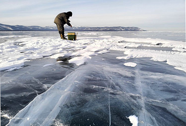 Подледная рыбалка на Байкале в Бурятии. Рыбак ловит омуля со льда