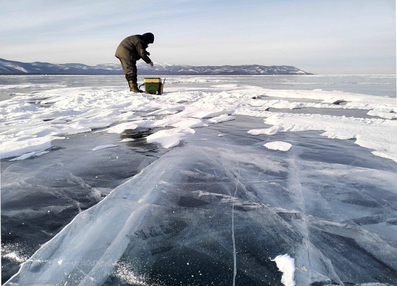 Подледная рыбалка на Байкале в Бурятии. Рыбак ловит омуля со льда