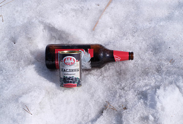 Пивная бутылка и банка из-под маслин на снегу