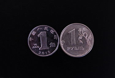 Деньги КНР и РФ. Монеты в один цзяо и один рубль на черном фоне
