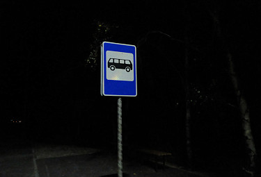 Дорожный знак возле автобусной остановки ночью