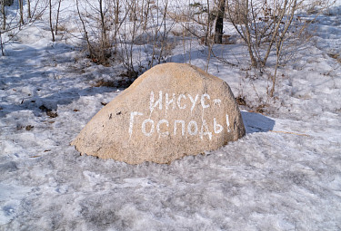 Надпись "Иисус - Господь!" на камне в зимнем поле