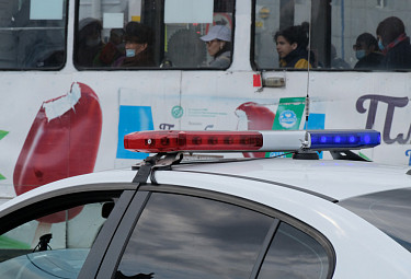 Полицейский автомобиль с мигалкой на фоне трамвая