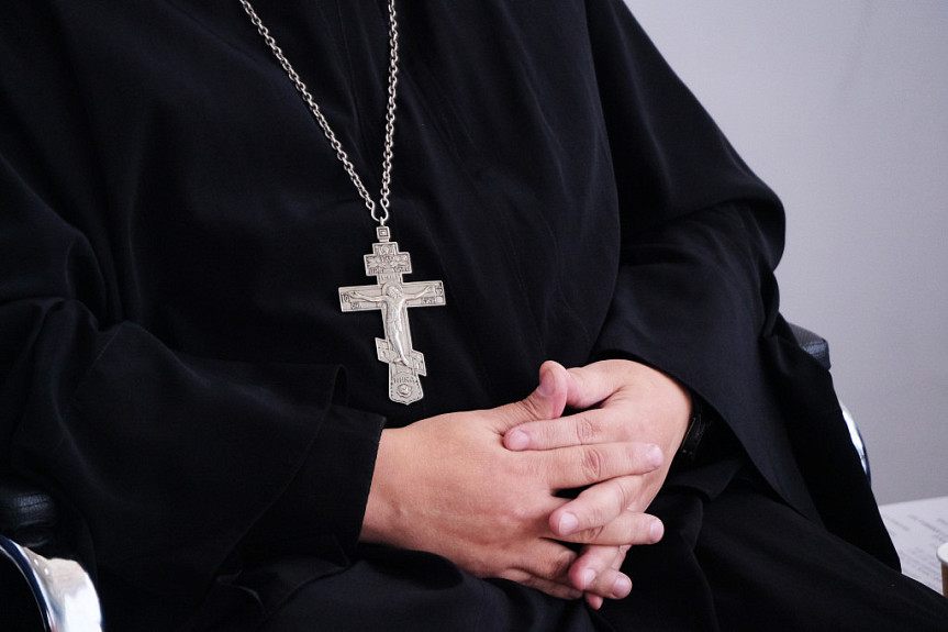Христианство. Православный священник в черной рясе и с крестом на шее