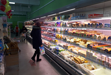 Покупатели у полок с продуктами в торговом зале супермаркета