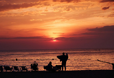 Люди на пляже наблюдают тропический закат над морем. Таиланд