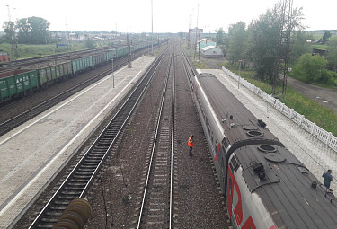 Железнодорожный рабочий стоит у железнодорожного состава с символикой РЖД 