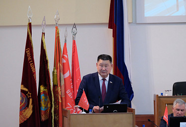 Вячеслав Мархаев выступает на фоне советских флагов и флага России