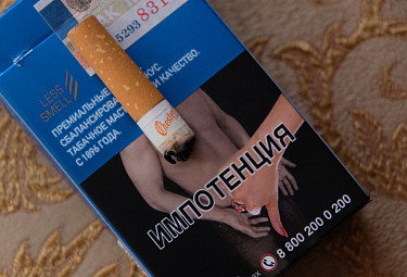 Окурок сигареты и пачка сигарет с устрашающей антитабачной картинкой об импотенции