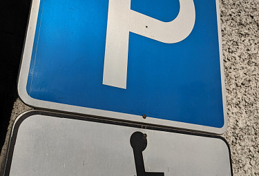 Знак парковки для инваоидов, прибитый к стене здания