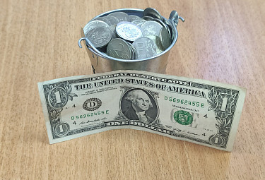 Ведерко с российскими монетами и долларовая купюра